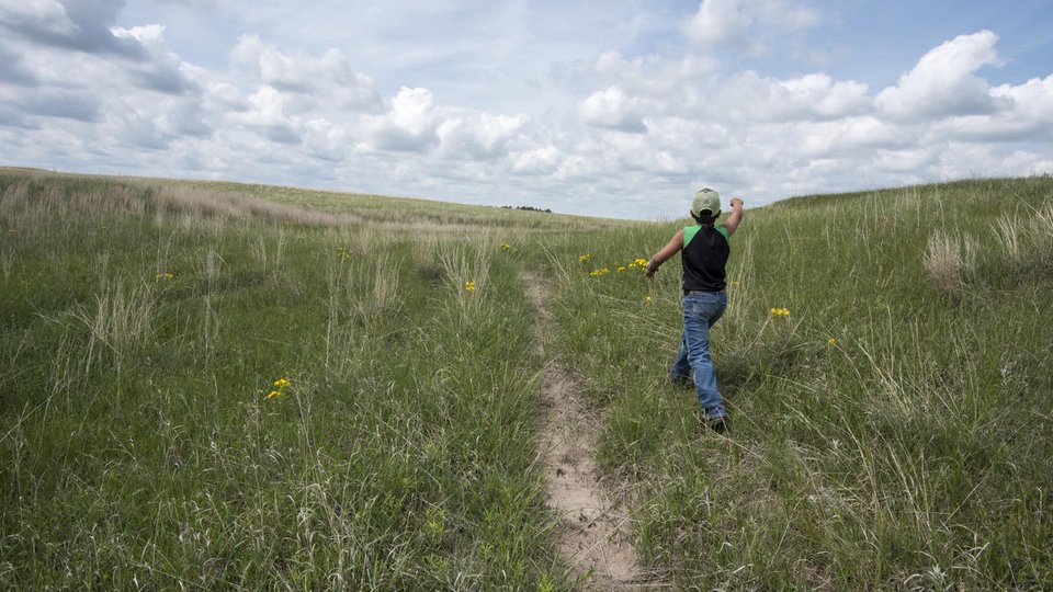 Boy runs through grasslands of his family ranch
