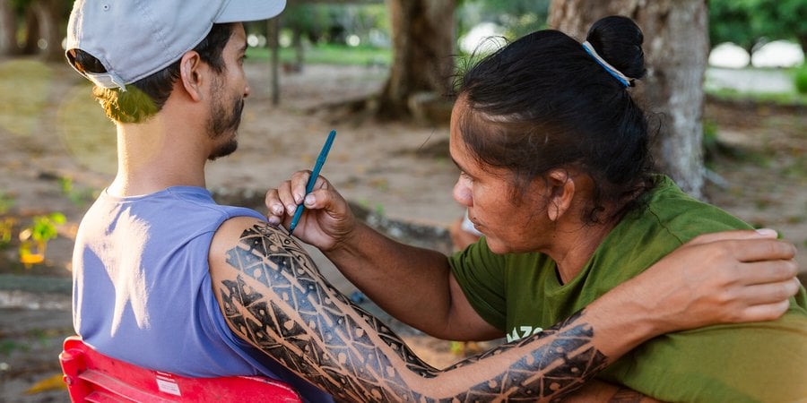 Woman paints mans arm with traditional designs
