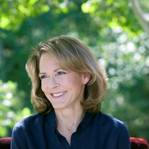 A woman smiles in front of a leafy green background