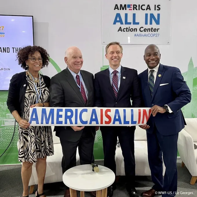 People hold a sign at the America is All In booth