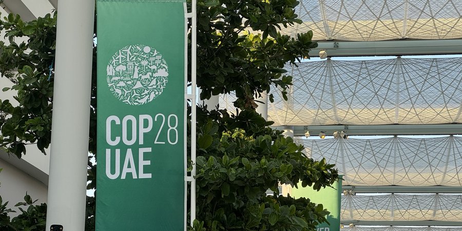 A vertical green sign reads COP28 at a building in Dubai