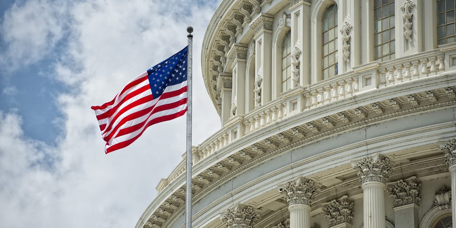 An American flag waves in the wind in front of the Capitol dome