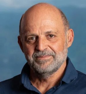 Headshot of Carlos Manuel Rodríguez, who has a salt and pepper beard and brown eyes.