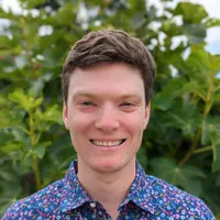 Wearing a blue shirt, Cody Aylward smiles at the camera. He has brown hair.