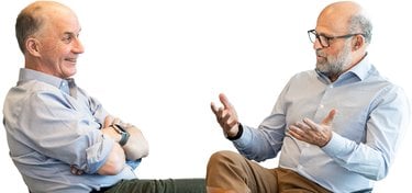 Two white men in business attire sitting and talking
