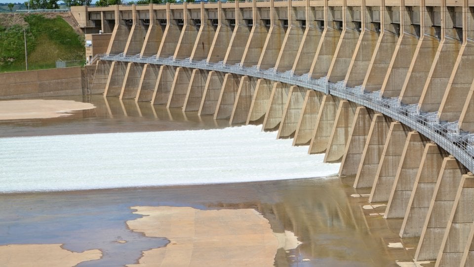 Image of a concrete dam in North Dakota. Water can be seen in the spill way.