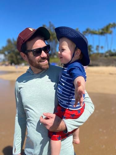 David Kuhn stands on the beach with his child