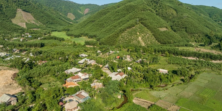 A color photo showing the a green mountain and valley with a blue sky in the background.