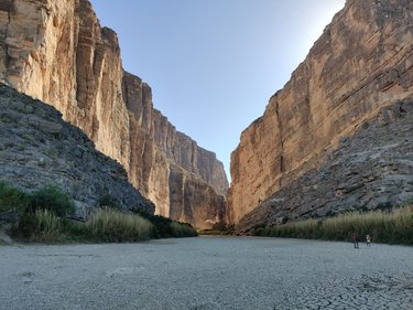 A cracked and dry riverbed is seen between a canyon