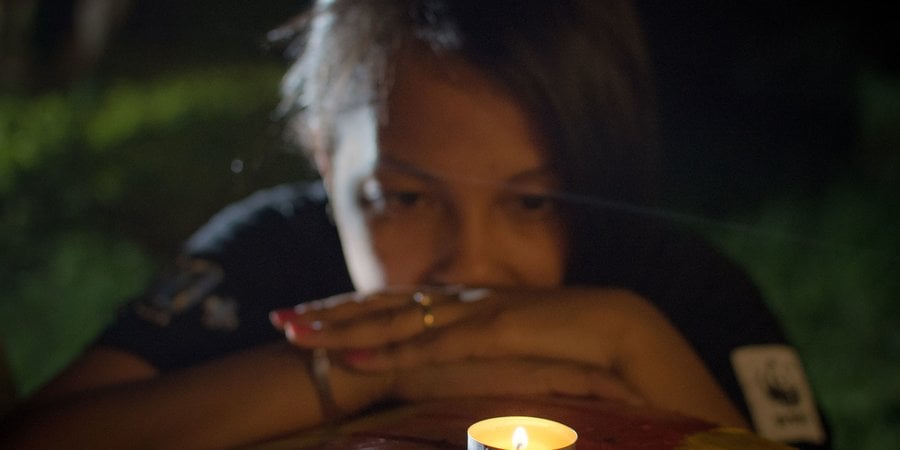 A woman reflects while looking at a candle
