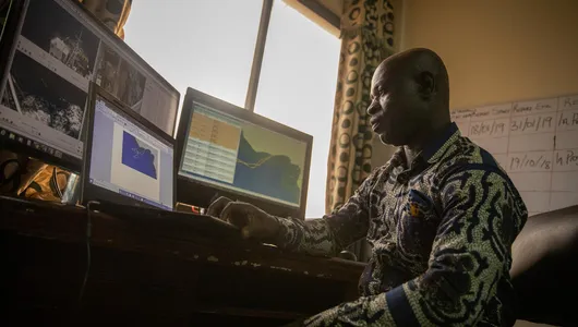 Richard Yeboah sits in front of a computer reviewing information from electronic monitors