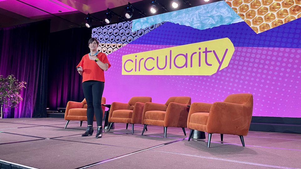 Erin Simon stands on a stage in front of a screen reading "circularity"