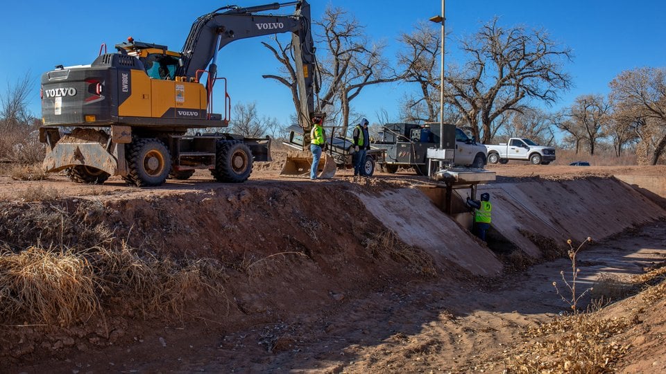 An excavator moving earth along ditch