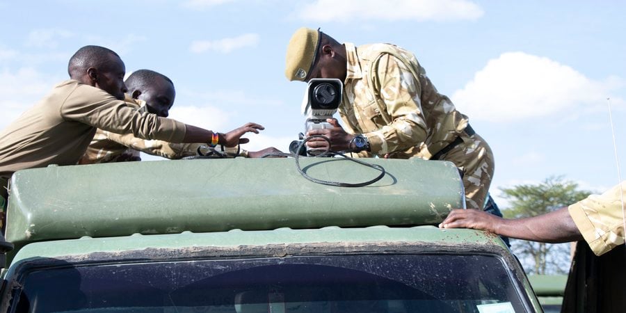 A person affixes a FLIR camera to the roof of a truck on a sunny day