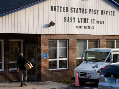 A person carrying a package enters teh East Lyme, CT Post Office