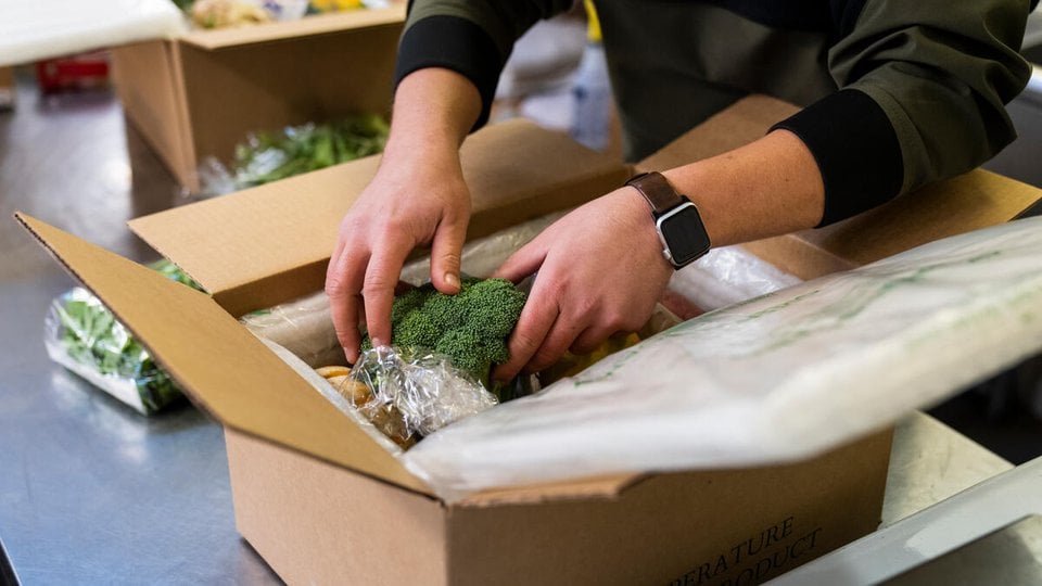 A person packs produce into a box