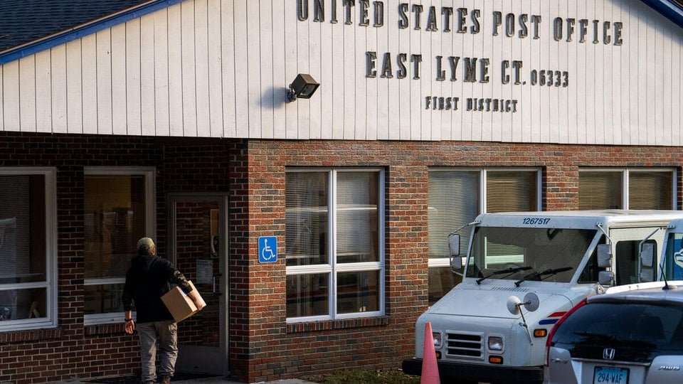 A person carrying a package enters teh East Lyme, CT Post Office