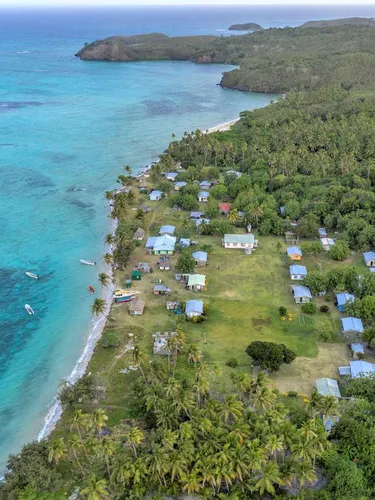 Aerial view of a fishing community along the coast nestled up against clear blue waters