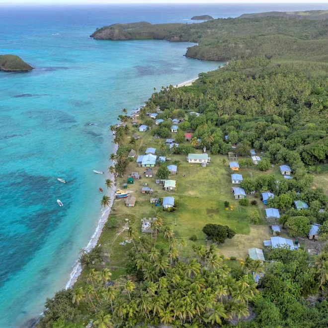 Aerial view of a fishing community along the coast nestled up against clear blue waters