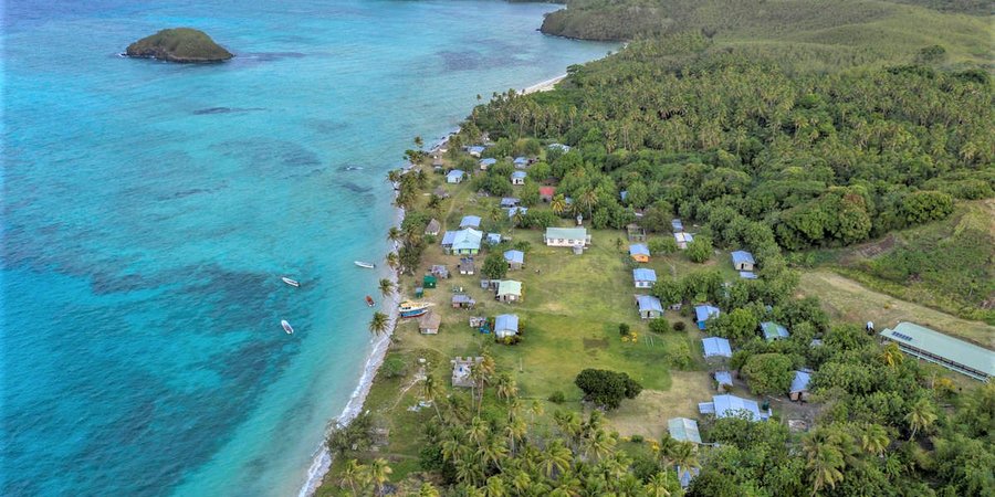 Aerial view of a fishing community along the coast nestled up against clear blue waters