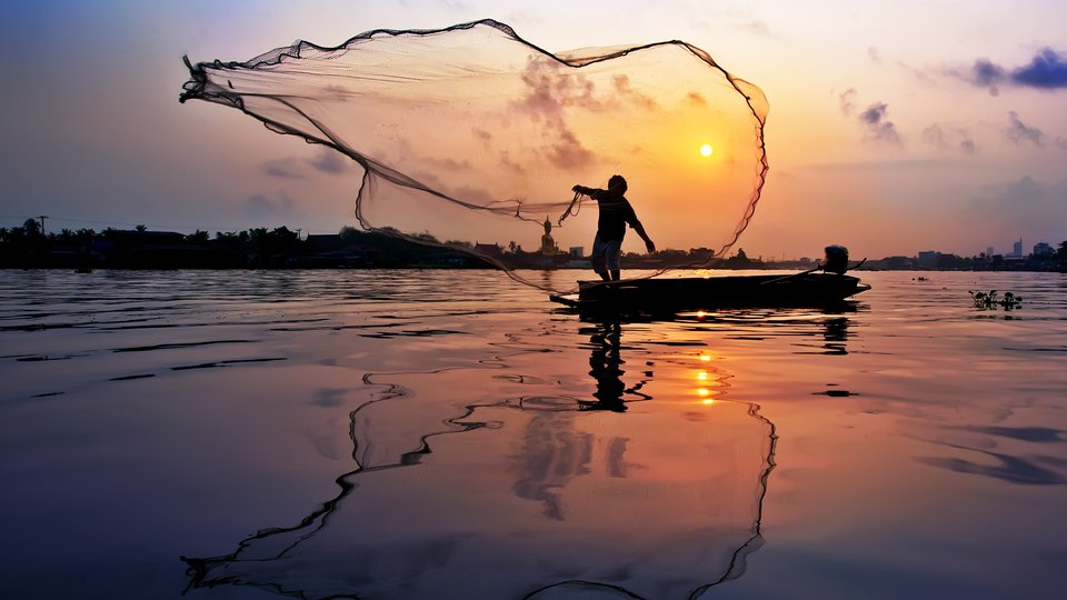Fisher casts a line at sunset on Chaophaya River