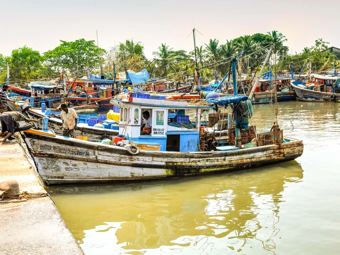 A brightly colored fishing boat tied up to a dock in India