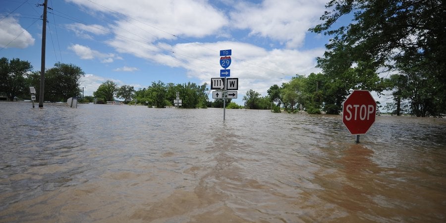 A street is severely flooded after a hurricane. The water level is at the height of a stop sign.