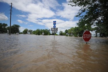 A street is severely flooded after a hurricane. The water level is at the height of a stop sign.