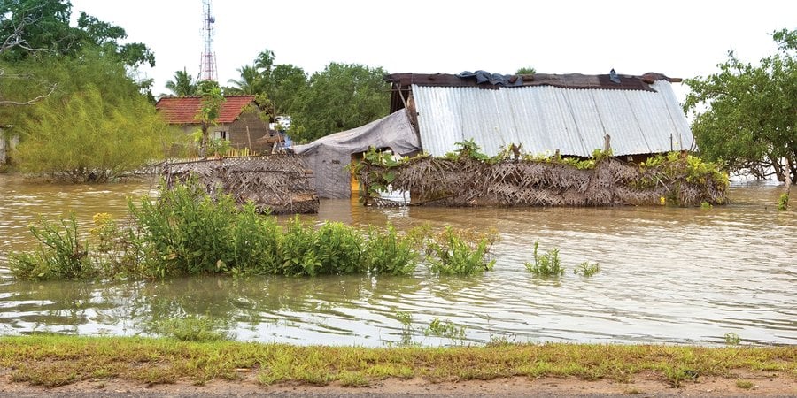 A photo showing flooding near a structure near trees.