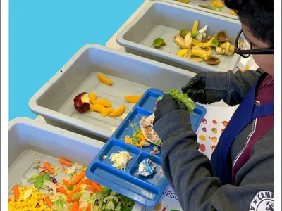 A report cover showing a student from above emptying a tray of food into different bins with compostable material
