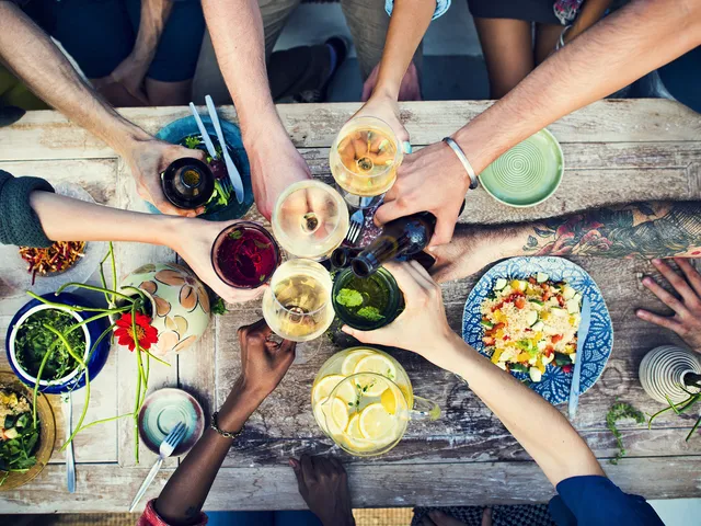 People sharing a dinner with hands holding cups