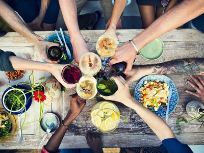 People surrounding table with food and cheersing