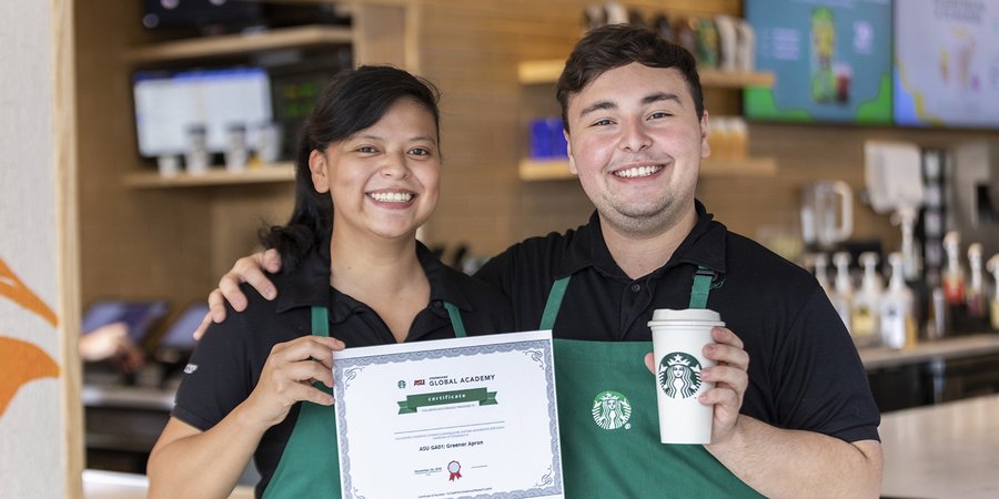 Two Starbucks employees hold up a Greener Apron certificaate