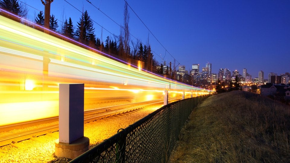 Light streams in a high-speed blurred photo of a train going toward a city at night