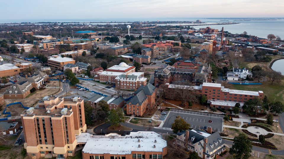 An aerial view of the Hampton University campus shows many brick buildings along a body of water