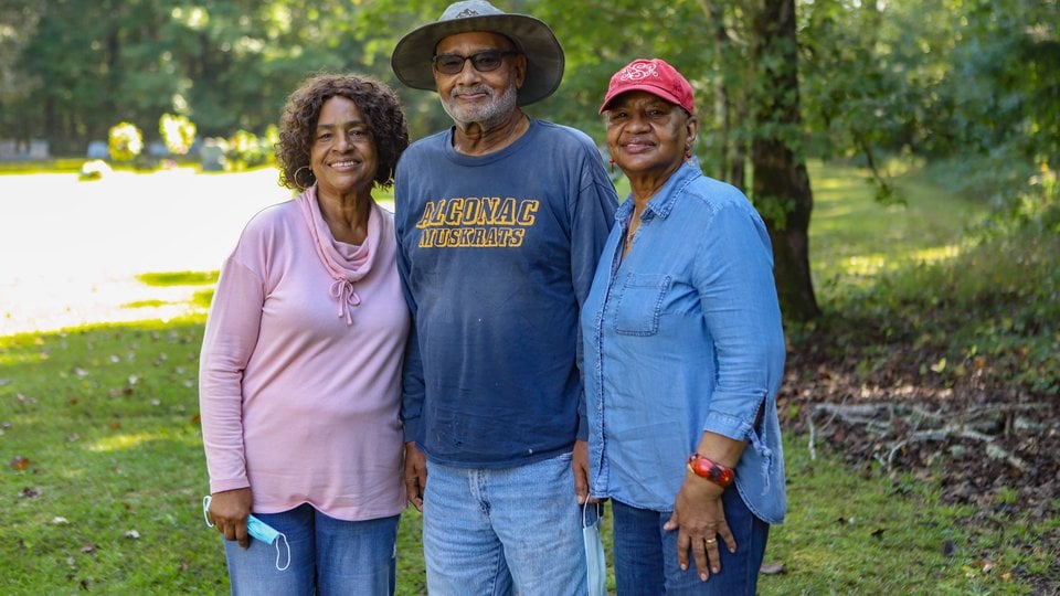 A family of three stands together facing the camera