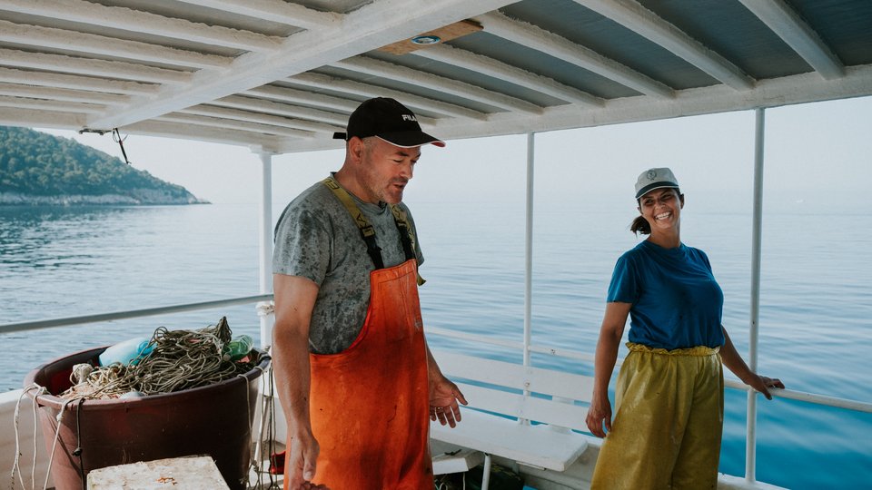 Dos personas están de pie en un barco y sonríen