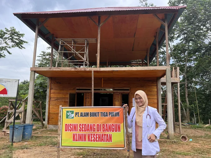 Herni stands in front of a sign outside of a building