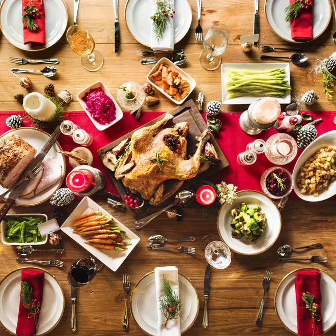 Aerial view of a festive table full of food and drinks on a red table runner