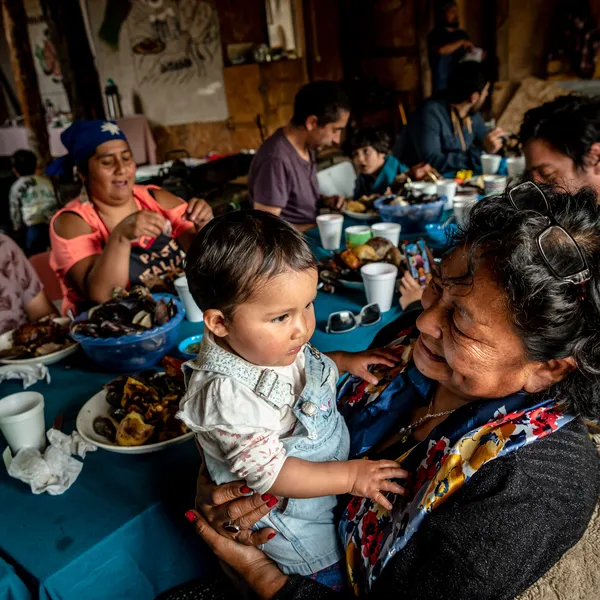 Generations of Huilliche families enjoy a curanto around a table