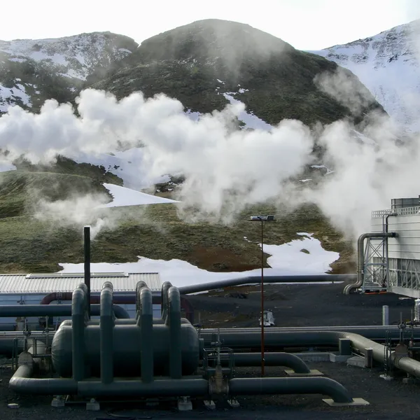 Smoke emits from a pipe at a hydrogen production plant with mountains in the background