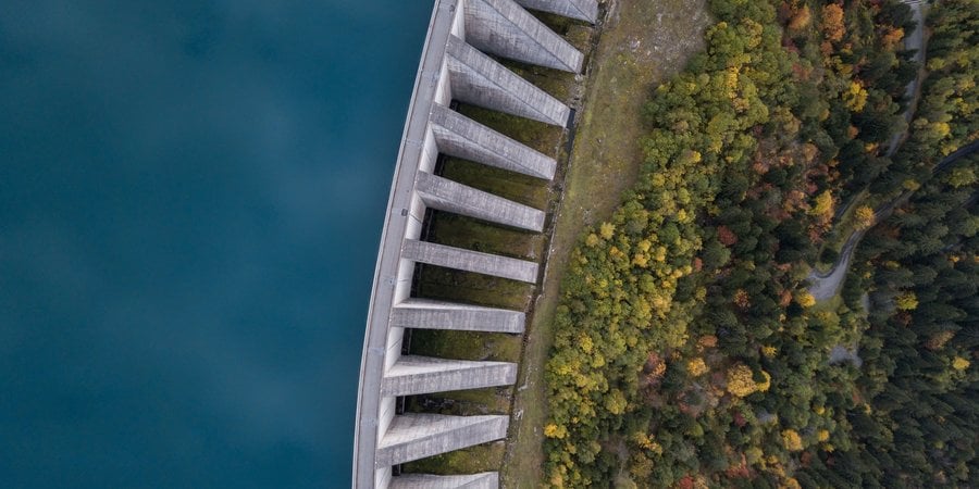 Aerial view of a hydropower dam with water on one side and forest on the other