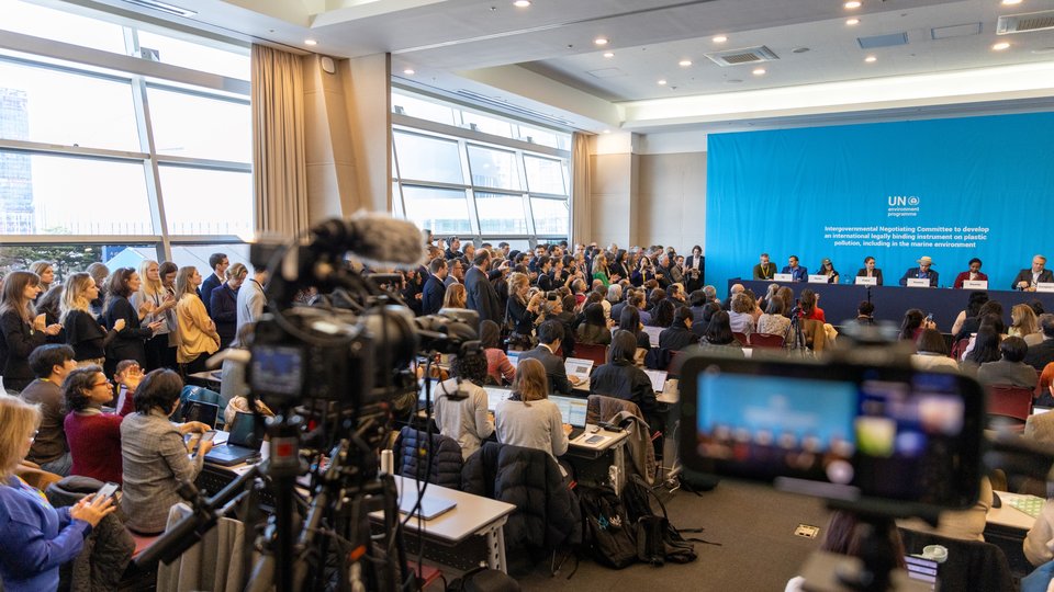 cameras recording in a packed room, with several people on stage