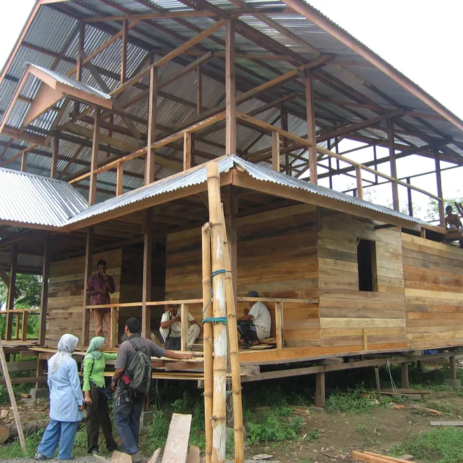 A house is being constructed amidst a backdrop of palm trees