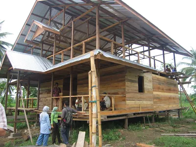 A house is being constructed amidst a backdrop of palm trees