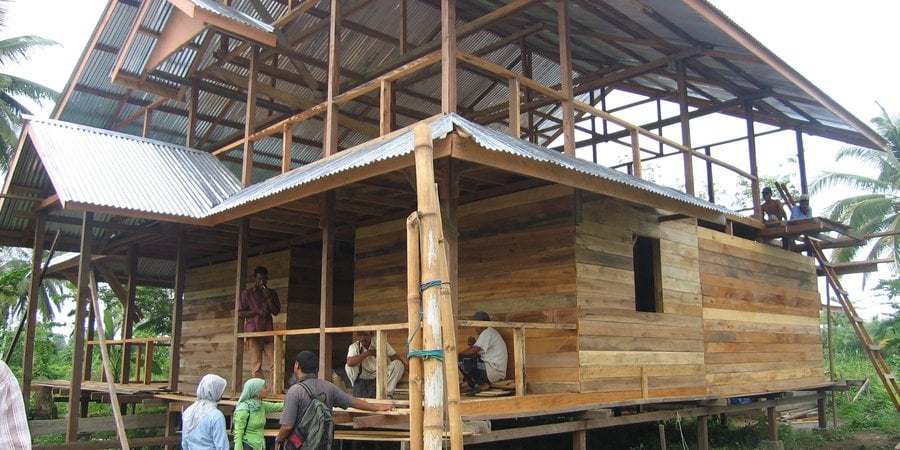 A house is being constructed amidst a backdrop of palm trees