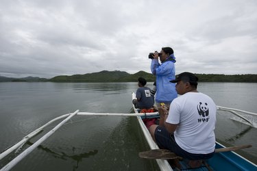 Three people on a makeshift boat patrolling a waterway.