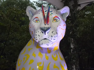 A photo showing a singular white jaguar statue with colorful paint decorating it.