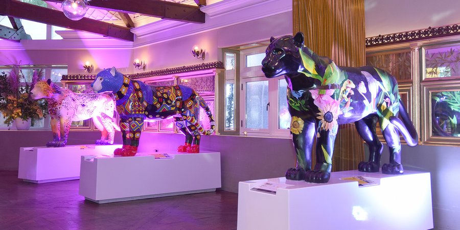 Painted jaguar statues on display at an indoor venue.