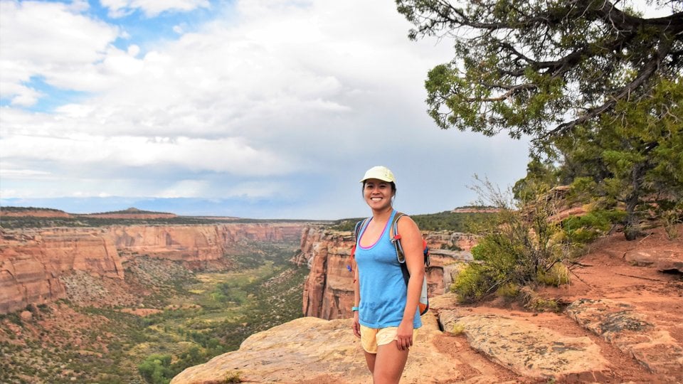 A color photo showing a woman in the foreground in summer clothing with the Grand Canyon in the background